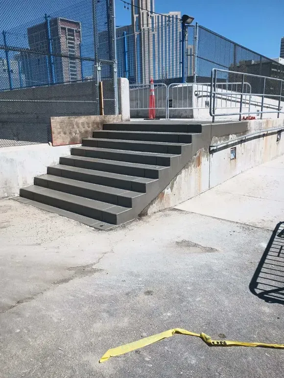 A set of stairs leading up to a ramp with a yellow tape on the ground.