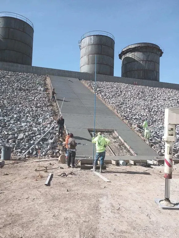 A group of construction workers are working on a concrete ramp