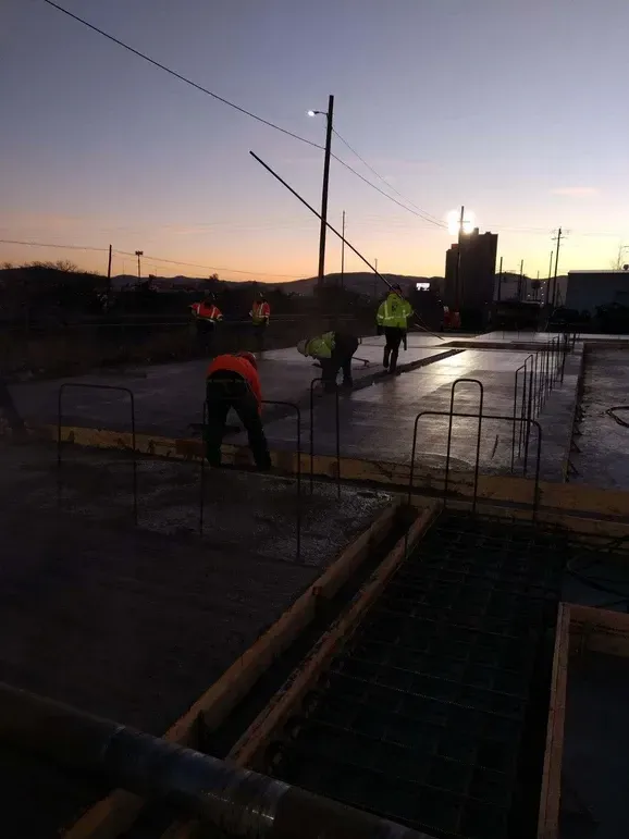 A group of construction workers are working on a concrete floor