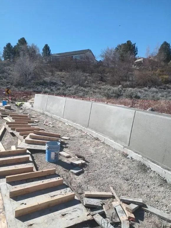 A concrete wall is being built in a dirt field