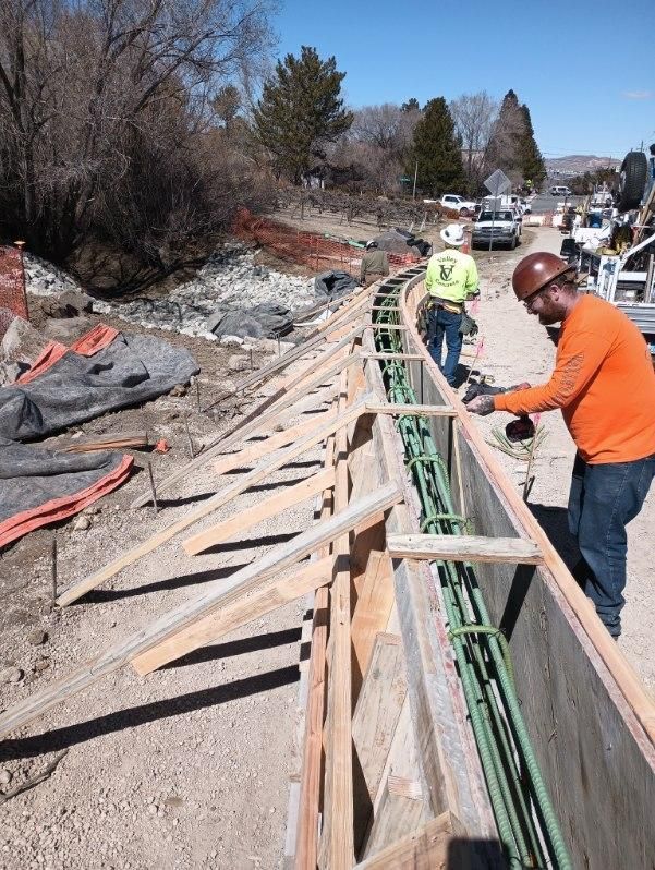 A man in an orange shirt is working on a construction site