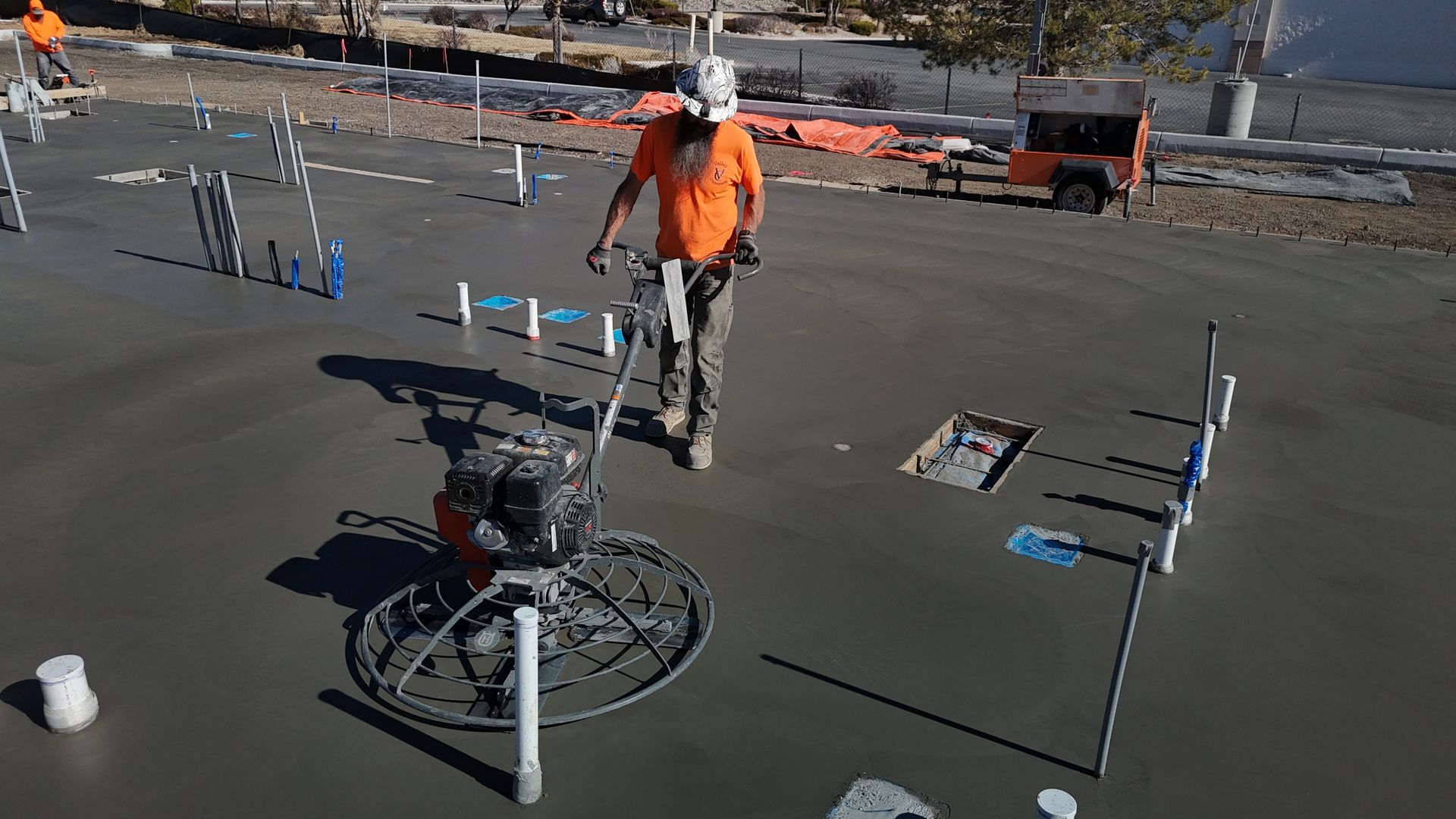 A group of construction workers are working on a concrete floor in front of a building.