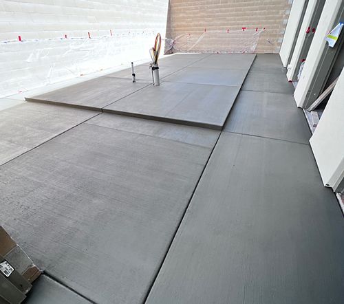 A gray concrete floor with a vase of flowers on it.