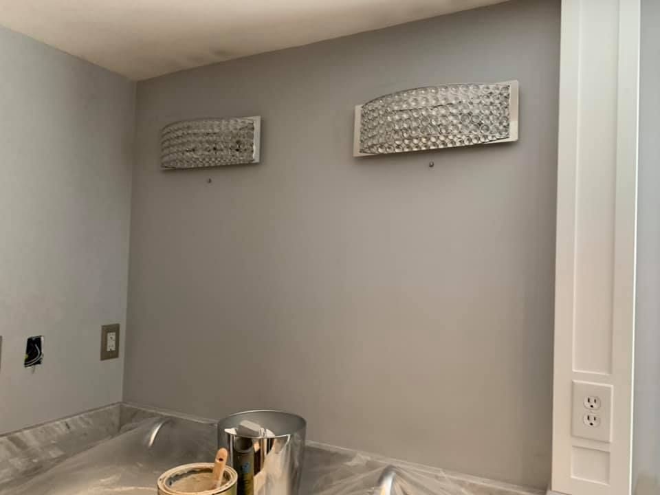 Paintbrushes and a roller lean against an orange painted wall.