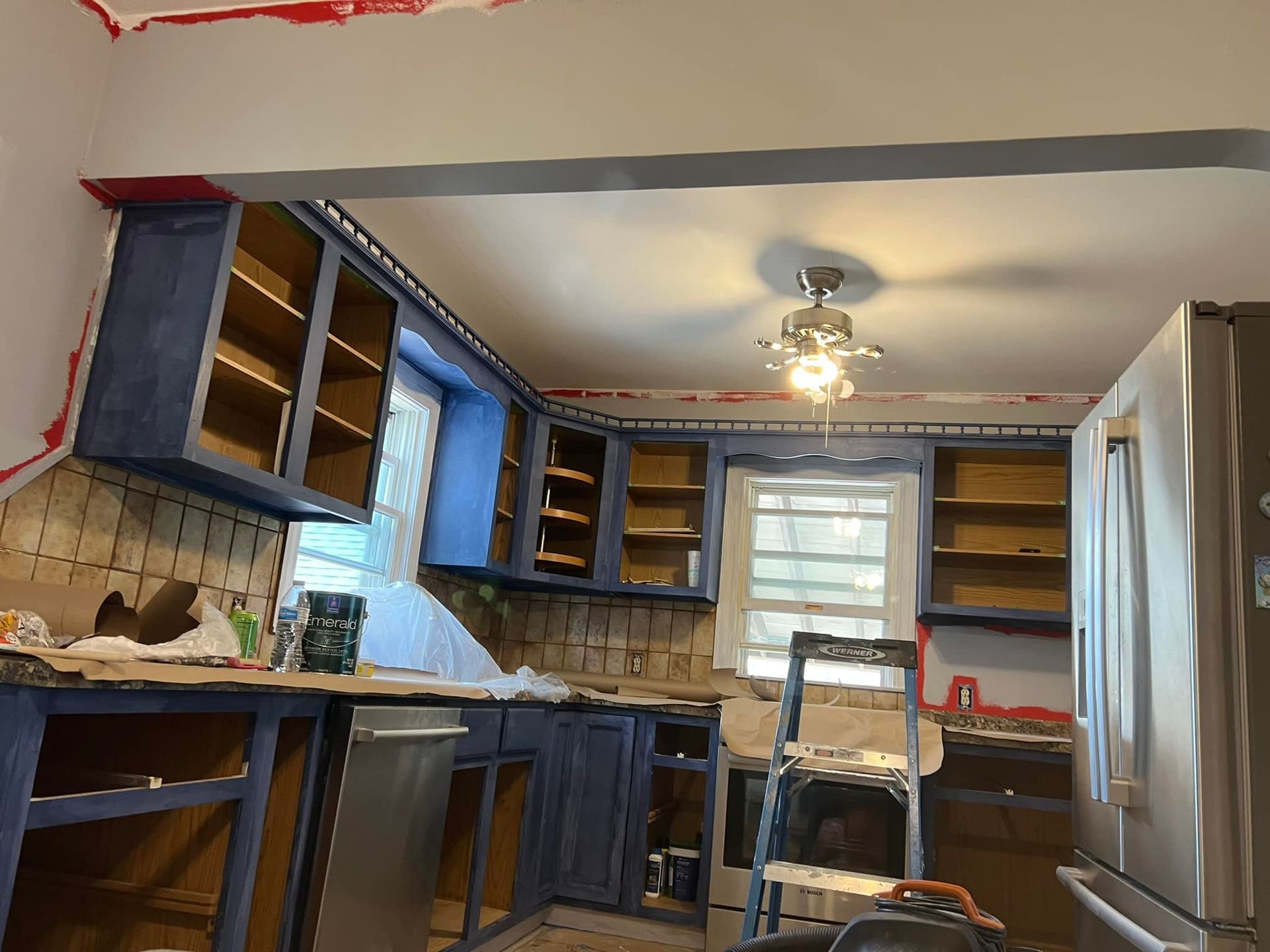 Kitchen under renovation with blue cabinets and a stainless steel refrigerator.
