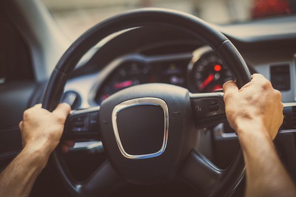 Hands gripping a black steering wheel inside a car, view of dashboard in background. | Torque European Car Care