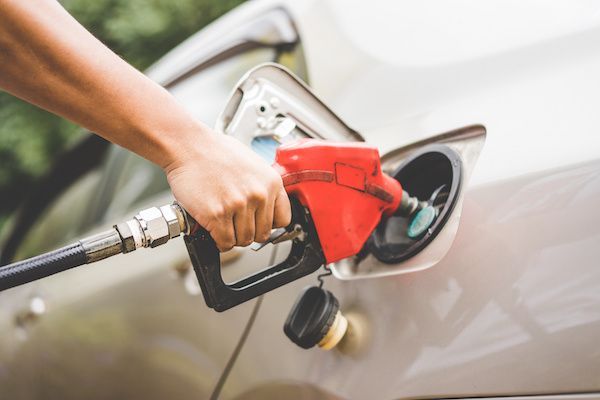 Hand fueling a car with a red gas pump at a gas station. | Torque European Car Care