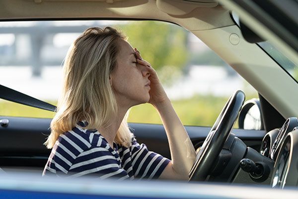 Woman in a car with head in hand, looking stressed, with hands on her face. | Torque European Car Care