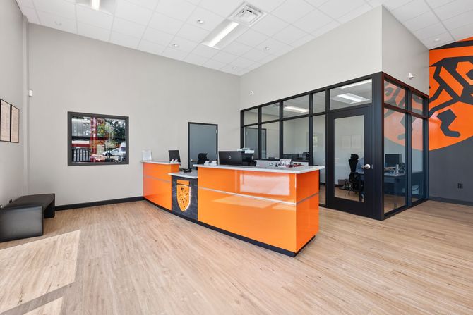 Waiting room with black chairs, magazines on table, and a doorway to another room. | Torque European Car Care
