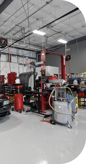 Auto repair shop interior with equipment, red lift, and oil tank. | Torque European Car Care