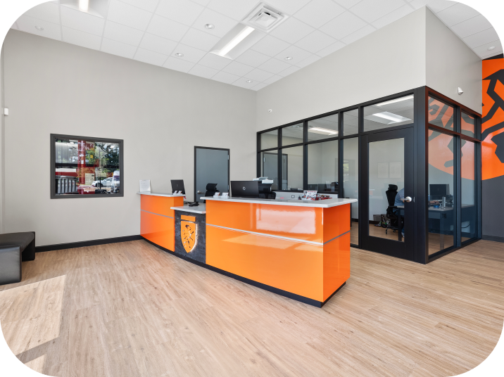 Orange and black reception desk in modern office, glass-walled office in the background. | Torque European Car Care