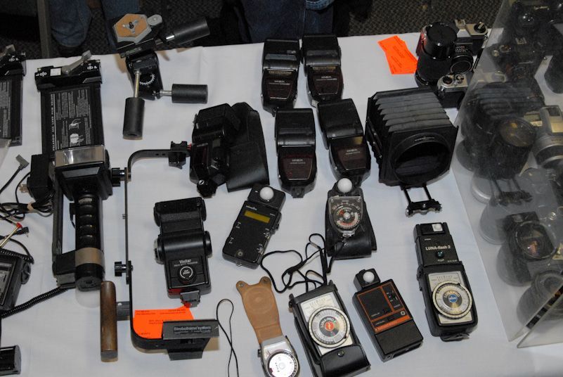 Woman in straw hat smiles, holding wine glass near a lake.