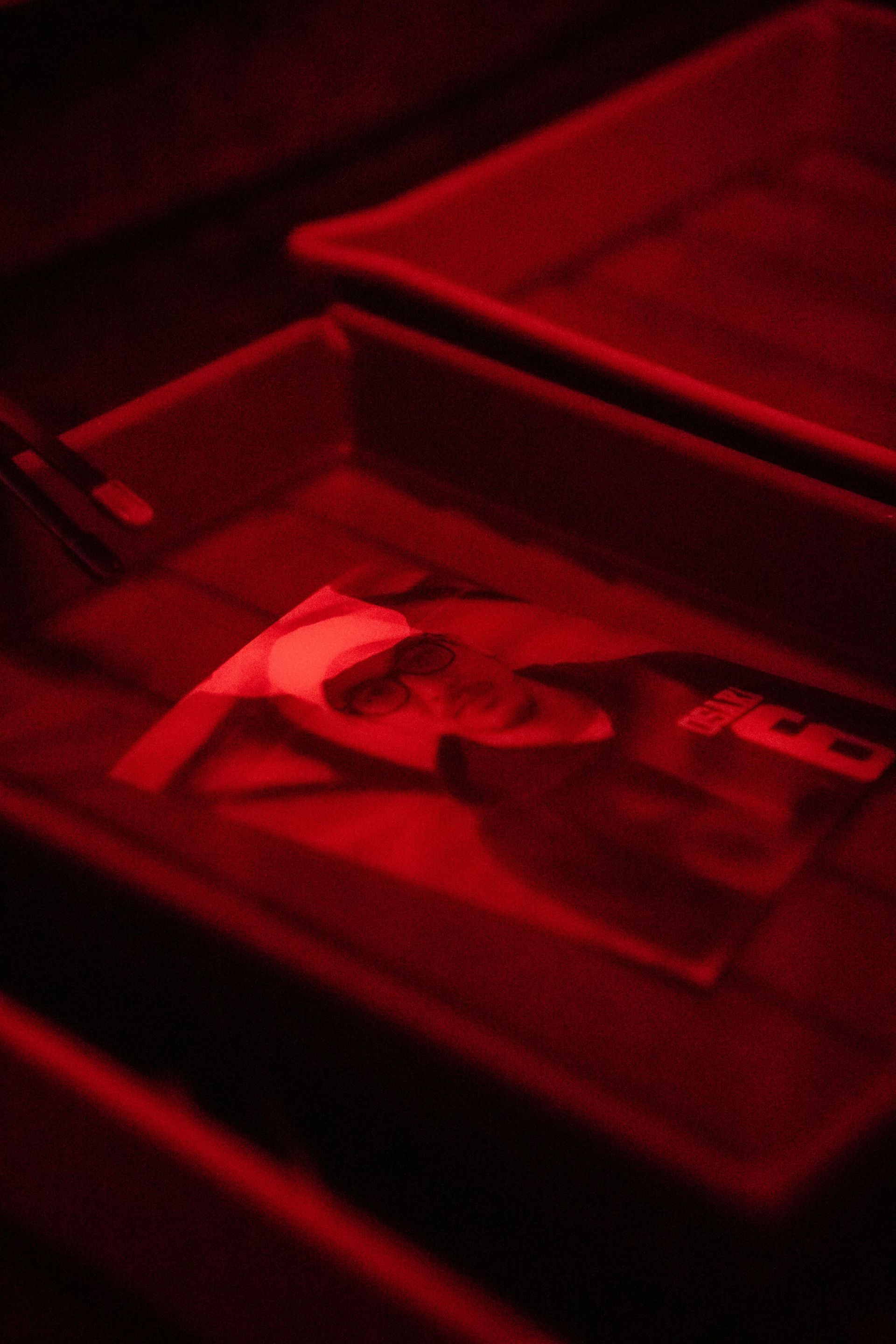 Woman in straw hat smiles, holding wine glass near a lake.