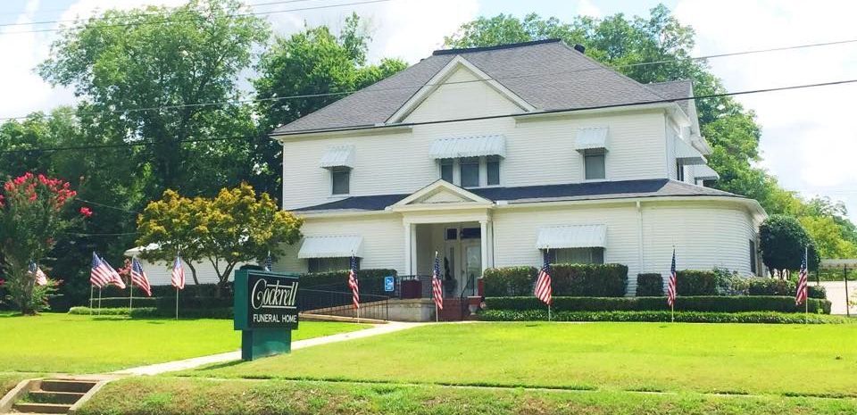 A large white building with columns and a tree in front of it