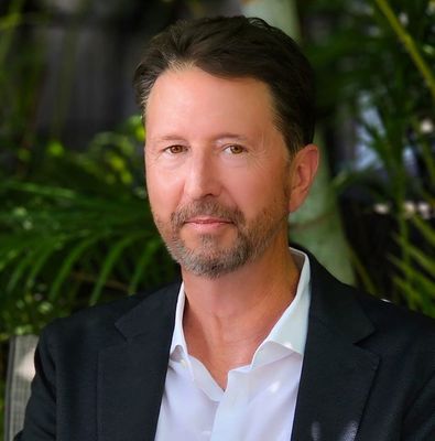 A man in a blue suit and white shirt is smiling for the camera.