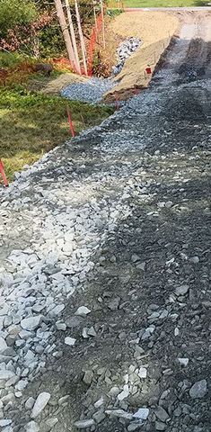 A gravel road is being built next to a grassy area.