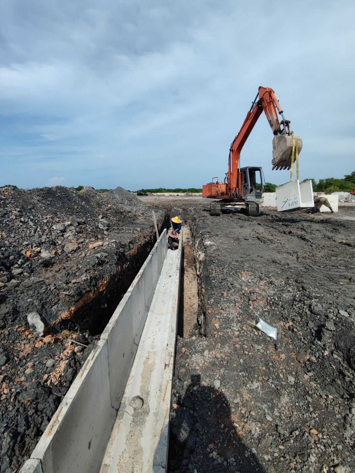 An excavator is working on a construction site next to a drain.