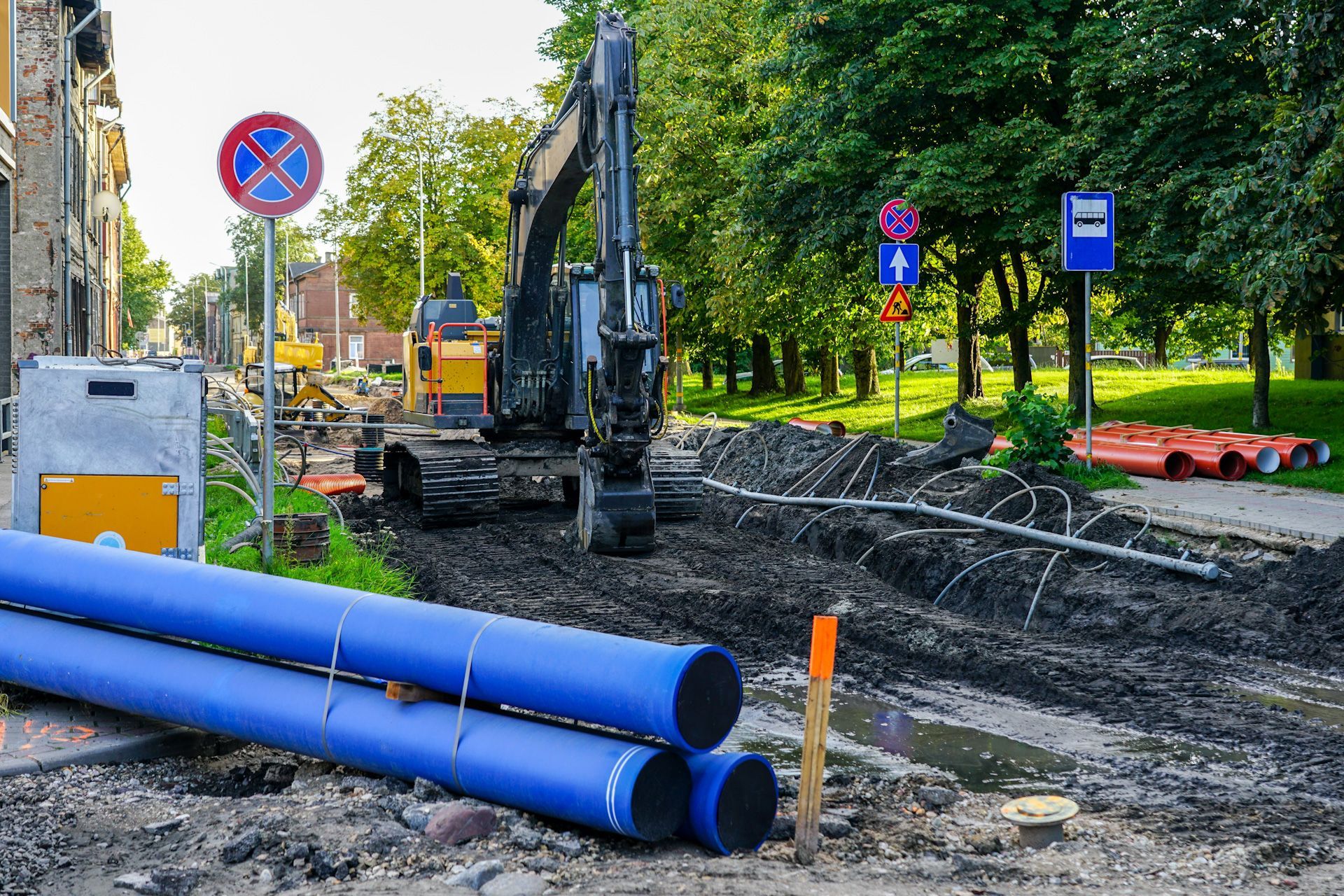 A construction site with blue pipes and a bulldozer in the background.