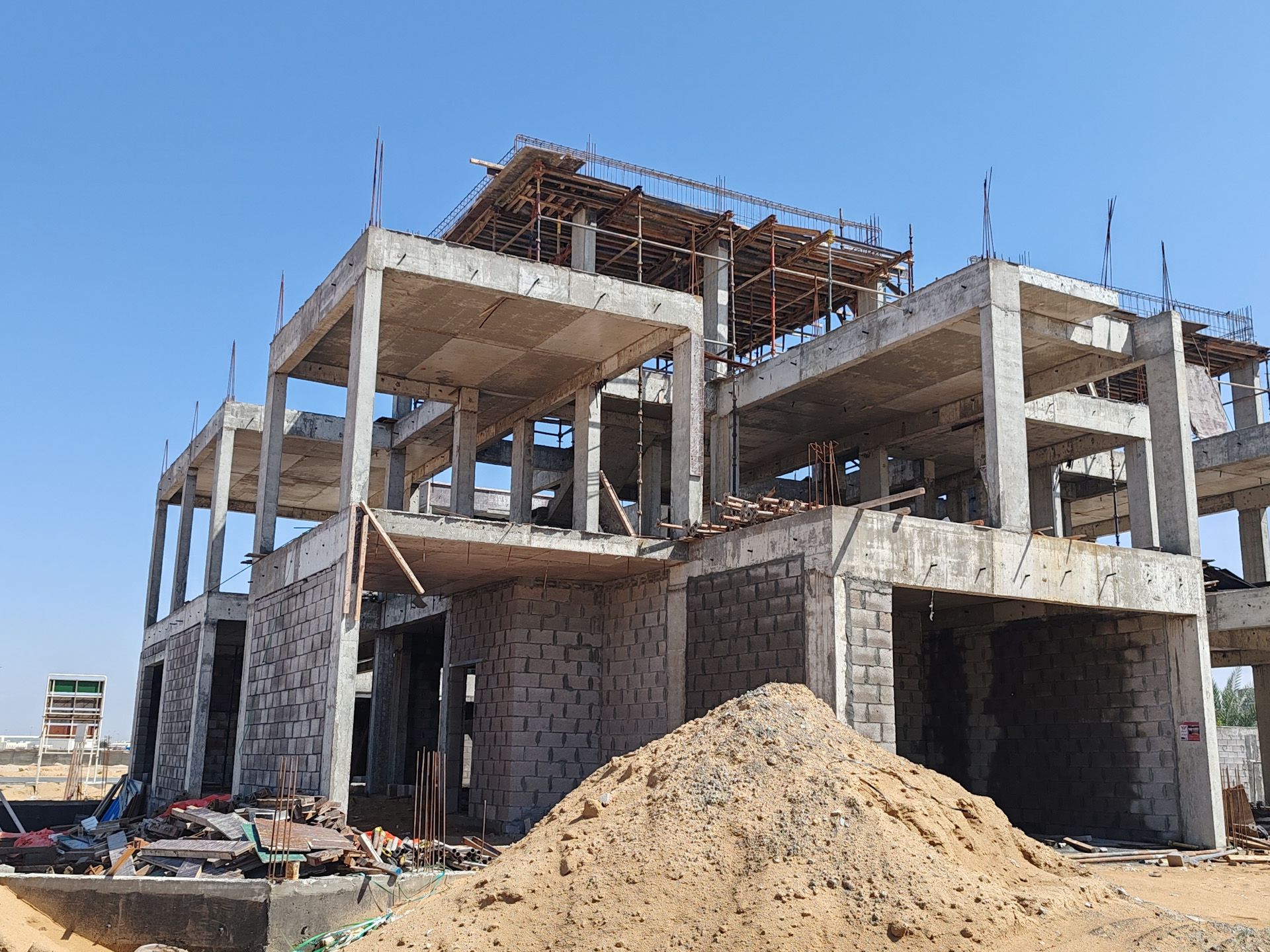 A large building under construction with a pile of dirt in front of it.