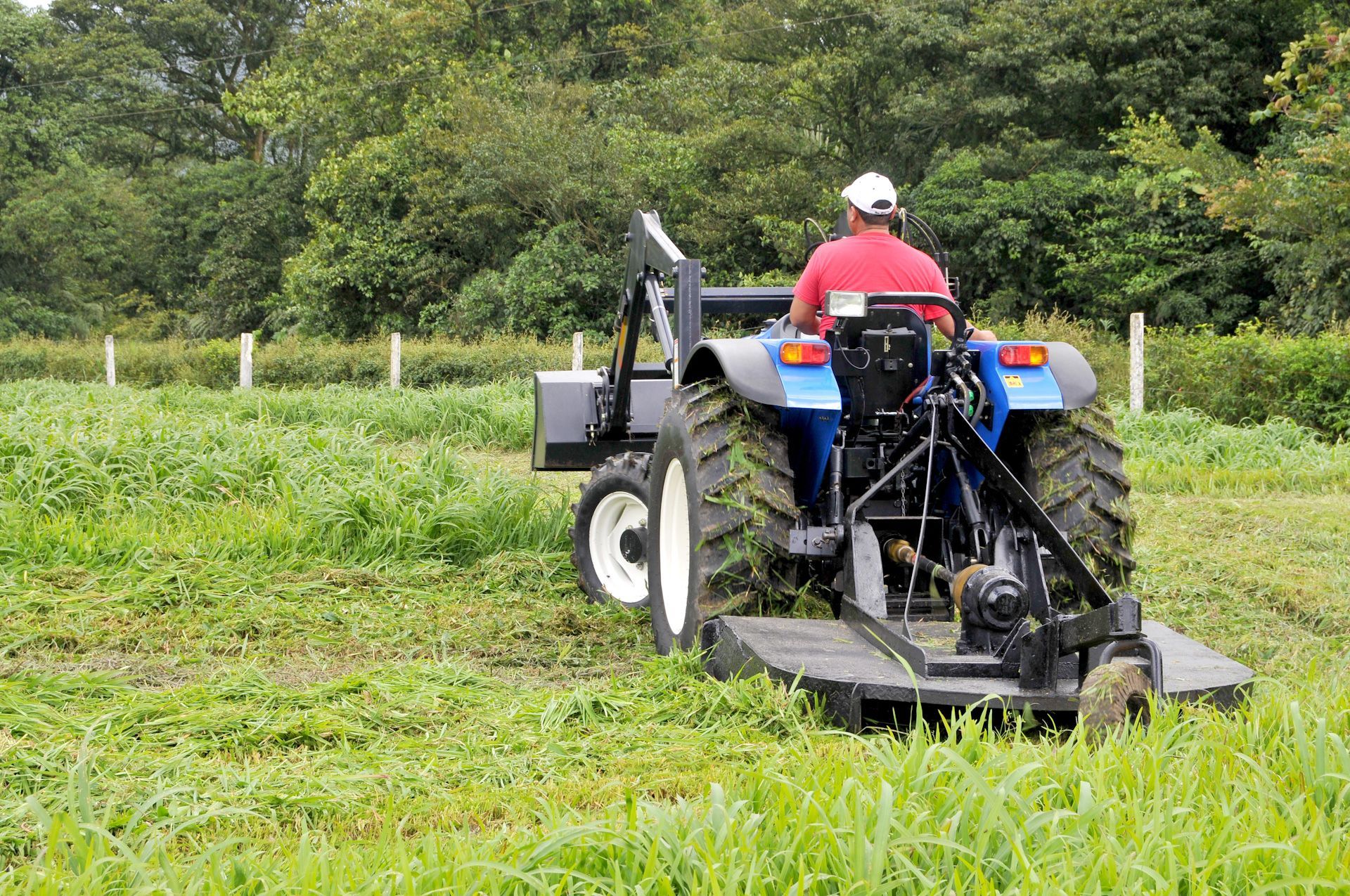 A man is driving a tractor through a grassy field.