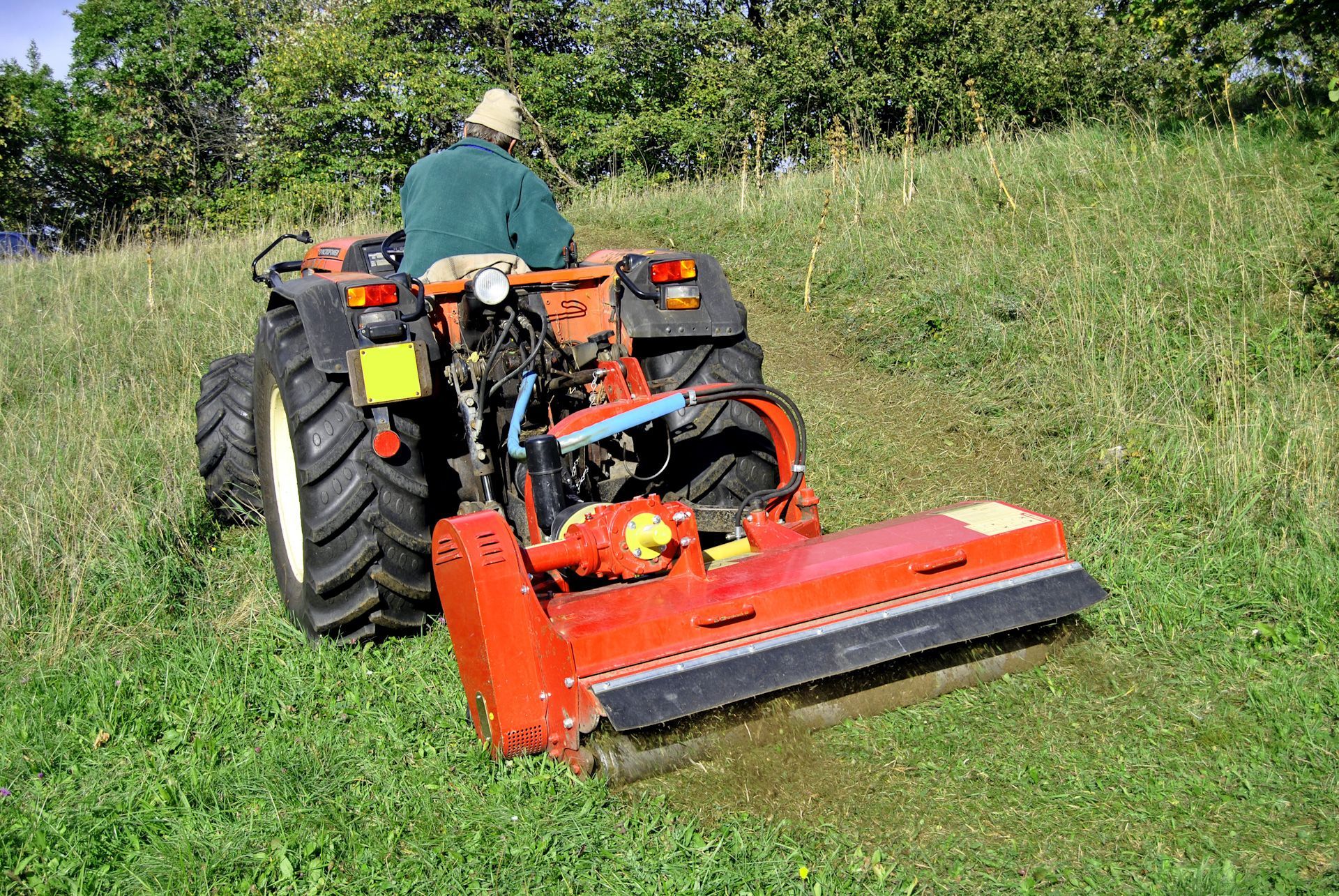 A man is driving a tractor through a grassy field.