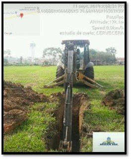 Un tractor está cavando un hoyo en el suelo de un campo.