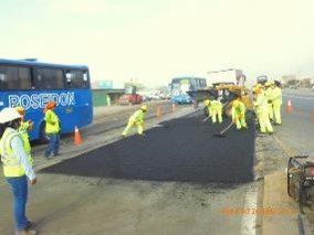 Un grupo de personas está trabajando en una carretera al lado de un autobús.