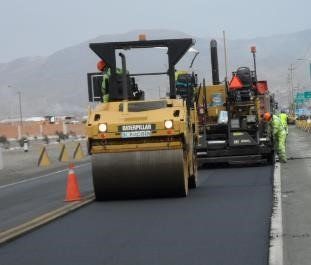Un rodillo asfáltico oruga amarillo está trabajando en una carretera