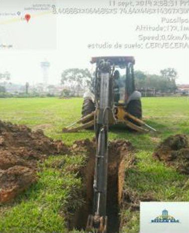 Un tractor está cavando un hoyo en el suelo de un campo.