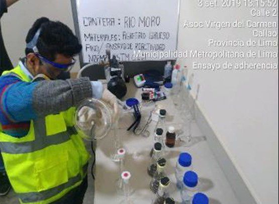 Un hombre con un chaleco amarillo está vertiendo líquido en una botella de vidrio.