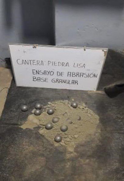 Un montón de bolas de metal están sobre una mesa al lado de un cartel.