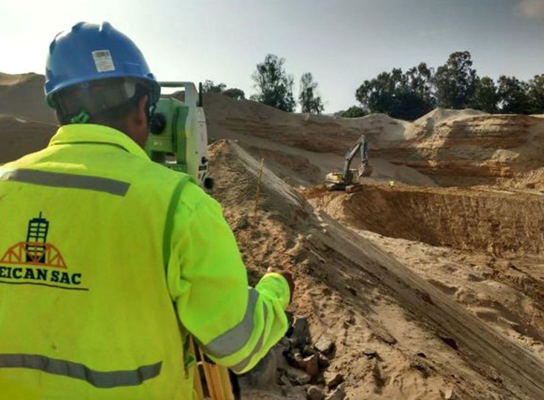 Un hombre que lleva un casco y una chaqueta amarilla está parado en el suelo.