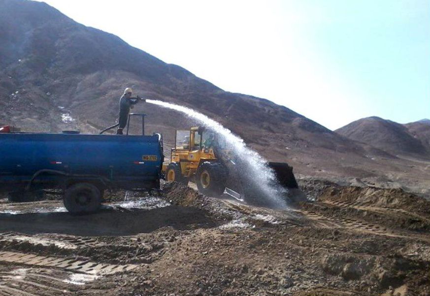 Un hombre está rociando agua desde una manguera en la parte superior de un camión azul.