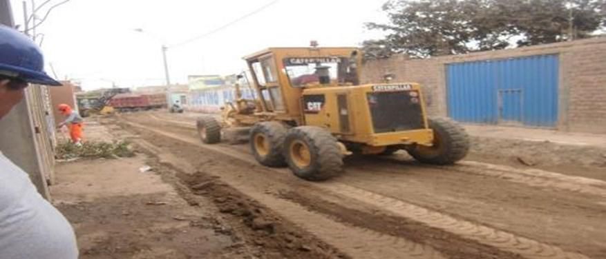 Un hombre con casco mira un tractor amarillo que avanza por un camino de tierra.
