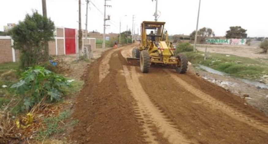 Un tractor amarillo conduce por un camino de tierra.