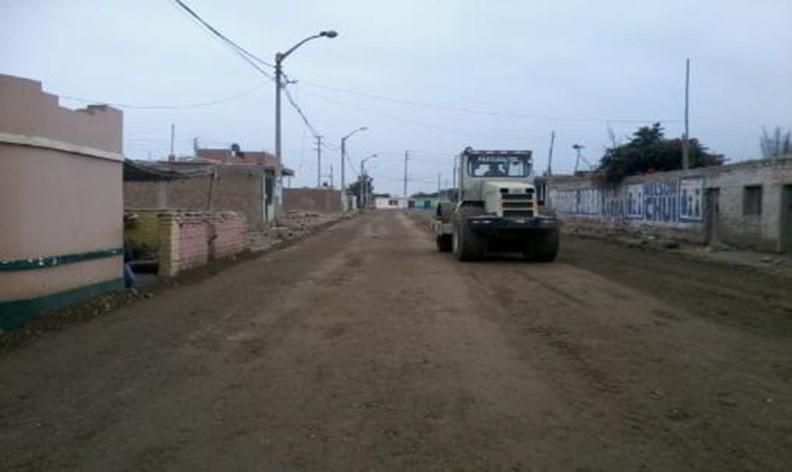 Un camión circula por un camino de tierra en un pequeño pueblo.