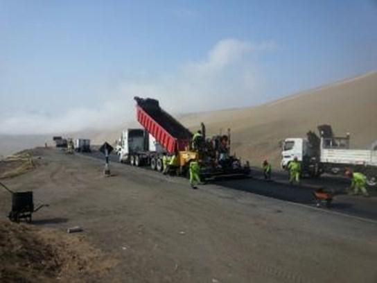 Una fila de camiones están estacionados al costado de una carretera.
