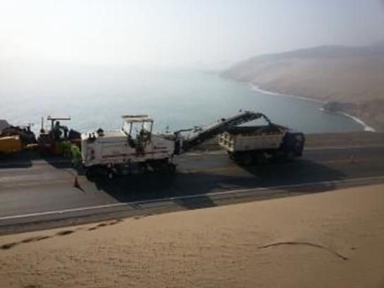 Un camión circula por una carretera al lado de un cuerpo de agua.