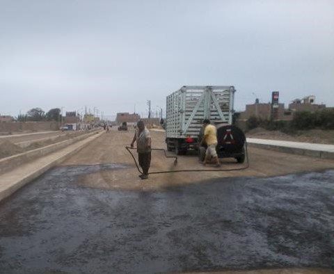 Un grupo de hombres está rociando asfalto en una carretera.