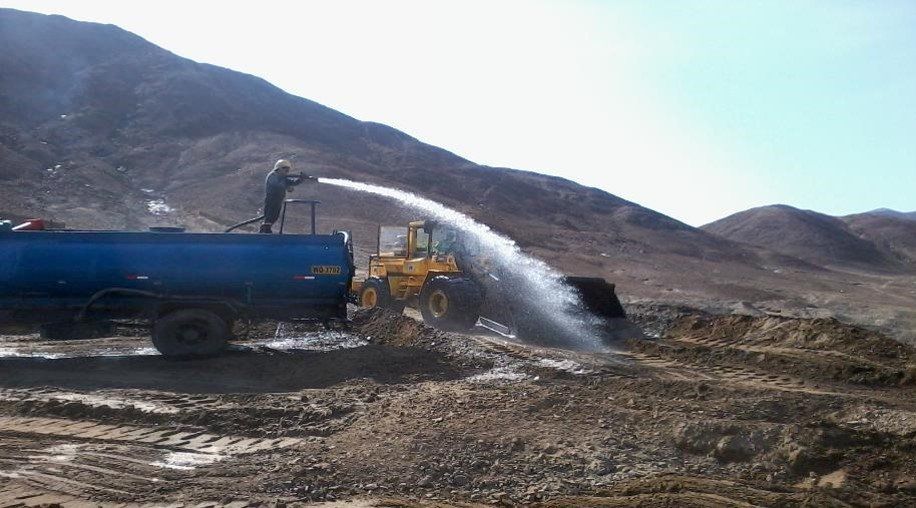 Un hombre está rociando agua desde un camión cisterna.