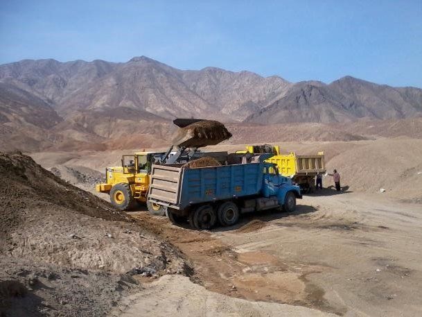 Un camión volquete está siendo cargado con tierra por una excavadora