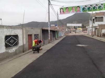 Un hombre empuja una carretilla por una calle.