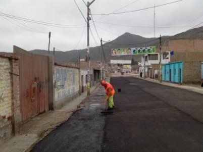 Un hombre está extendiendo asfalto al costado de una carretera.