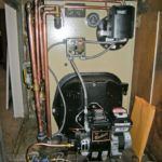 A boiler with a lot of wires coming out of it is sitting in a room.