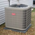 A large air conditioner is sitting outside of a house.