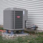 A large air conditioner is sitting on the side of a house.