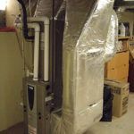 An air conditioner is sitting in a basement next to a wall.