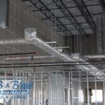 A building under construction with a lot of pipes hanging from the ceiling.