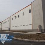 A large white building with a lot of windows is sitting next to a road.