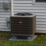 A large air conditioner is sitting on the side of a house.